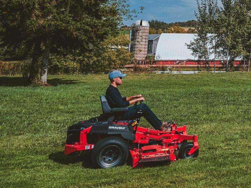 Extensive Field Maintenance with Riding Mower Outdoor maintenance worker riding a mower across a large field.