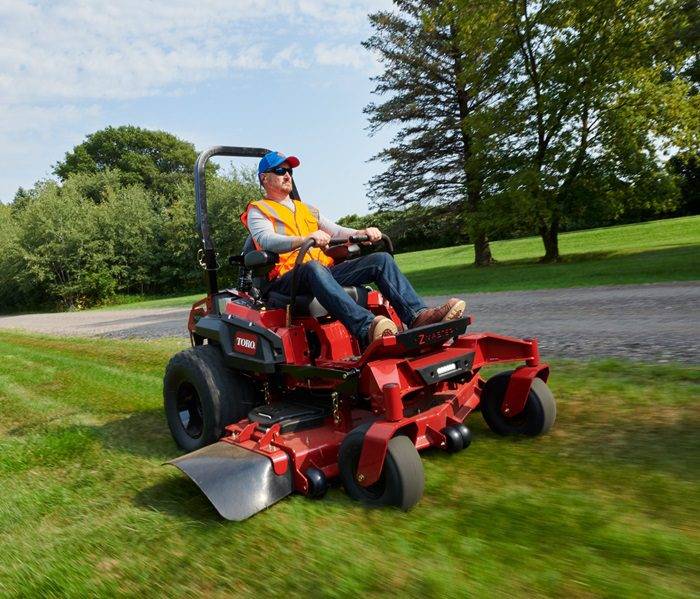Efficient Grass Cutting with Riding Mower Professional gardener mowing the grass with a riding mower in a residential backyard.